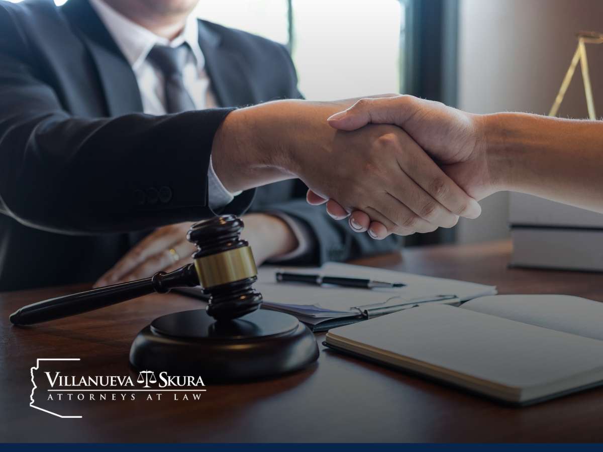 Two individuals shaking hands across a table in a lawyer's office, symbolizing the resolution of spouse rape charges